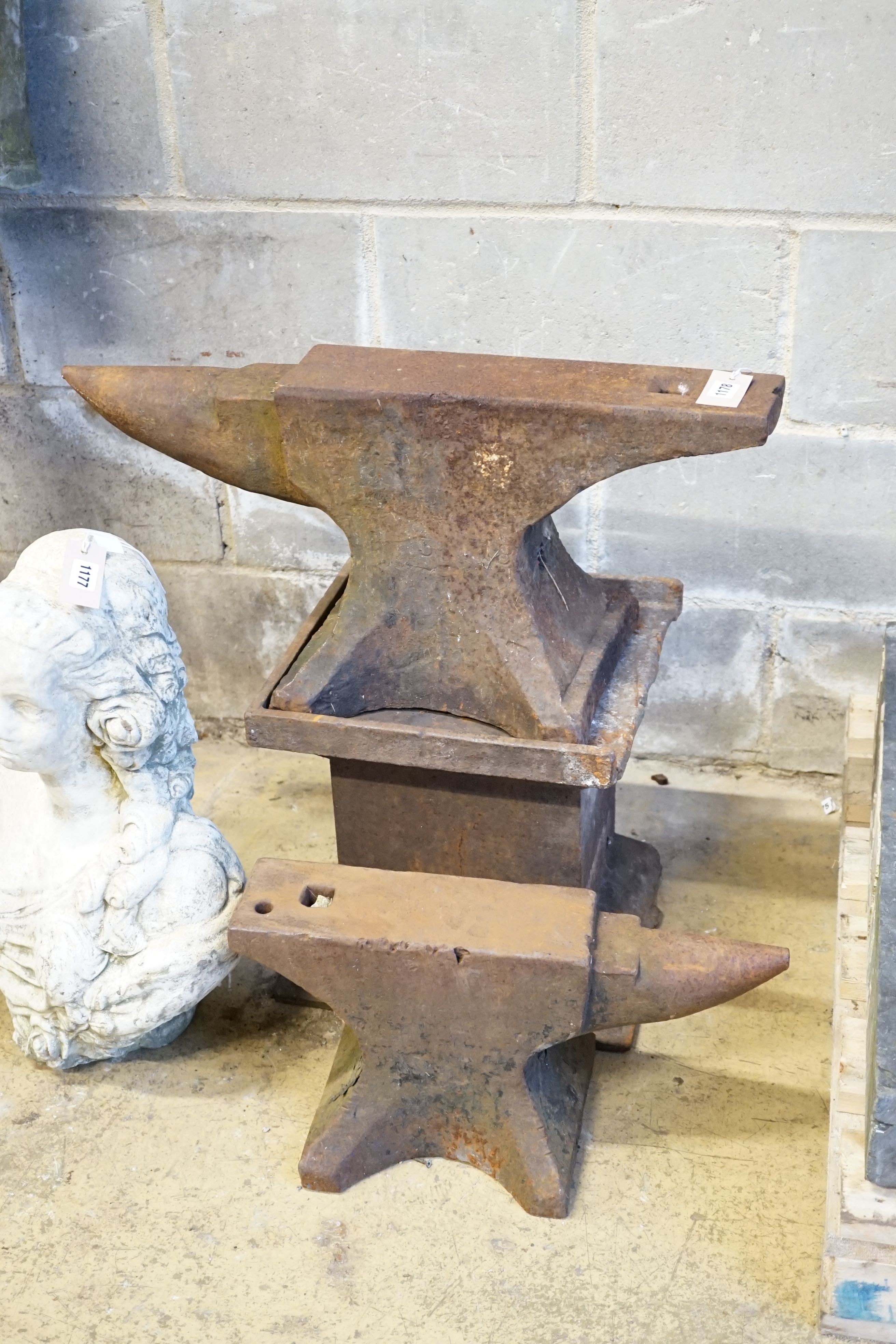 A cast iron anvil on stand, width 68cm, height 65cm and a smaller anvil, width 48cm
